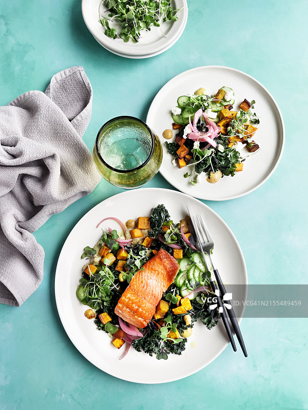 烤三文鱼配新鲜沙拉，置于蓝绿色背景上图片素材