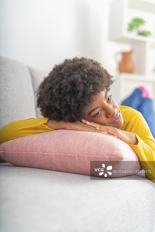 在沙发上休息并拥抱枕头的非裔美国妇女图片素材