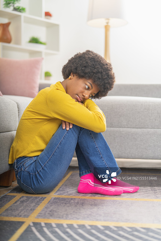 坐在客厅地板上拥抱自己的非裔美国女人图片素材