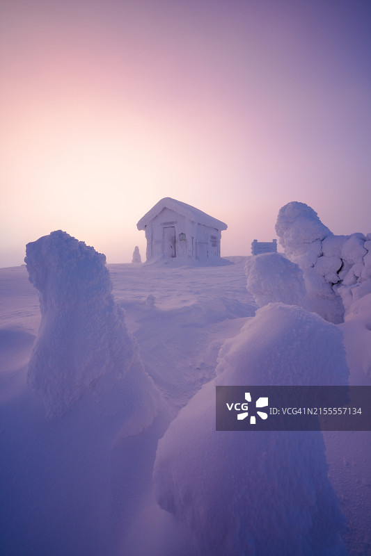 黎明时分被雪覆盖的冰冻山间小屋图片素材