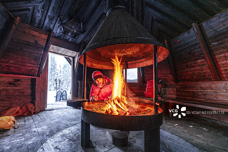 徒步者在山间小屋的壁炉旁取暖图片素材
