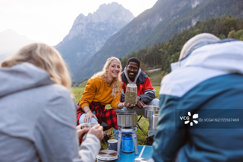 多种族夫妇在户外一起准备咖啡，对着镜头微笑图片素材