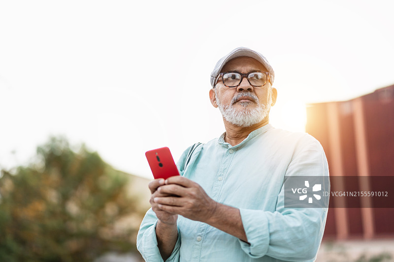 优雅的西班牙裔男人在日落时分使用手机APP图片素材