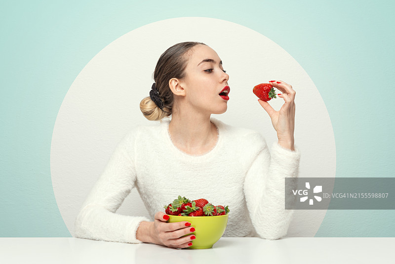 女人在桌上吃新鲜草莓图片素材