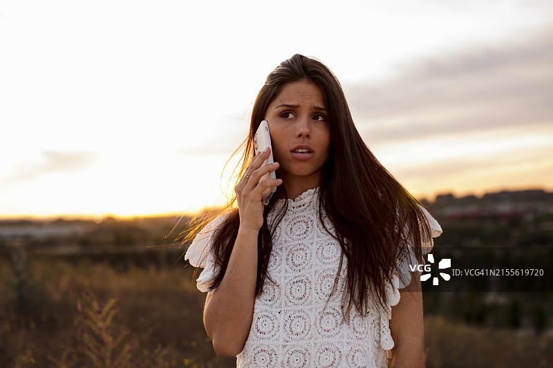 手持手机，面露忧虑和悲伤的年轻女孩，失望图片素材