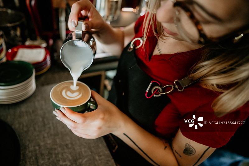 咖啡师制作拉花艺术，焦点在牛奶咖啡杯中图片素材