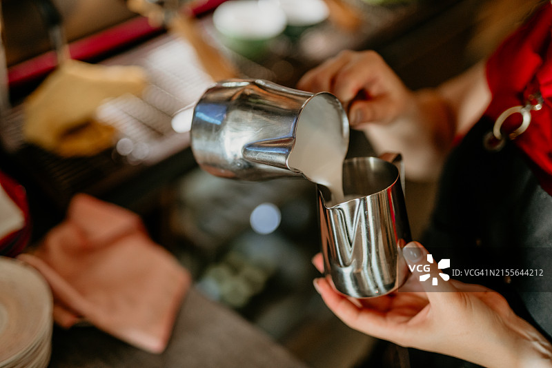 咖啡师制作拉花艺术，焦点在牛奶咖啡杯中图片素材