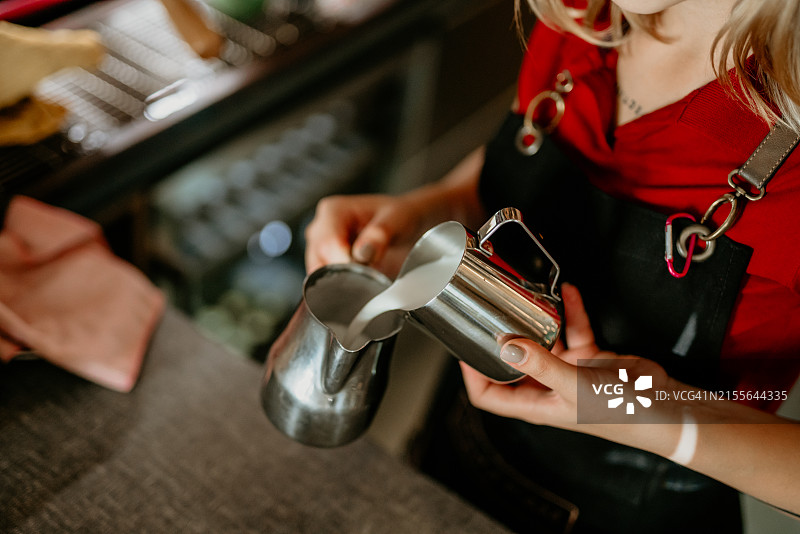 咖啡师制作拉花艺术，焦点在牛奶咖啡杯中图片素材