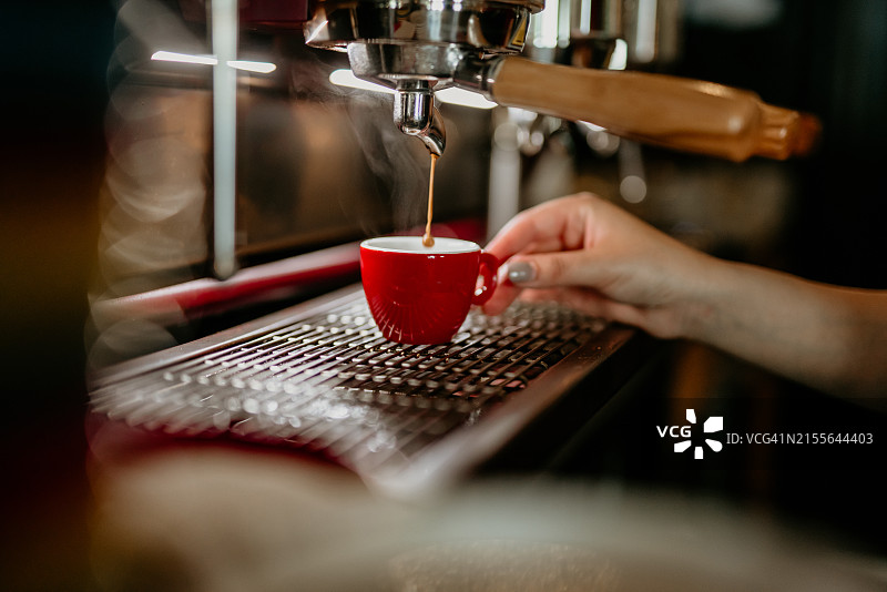 快乐的年轻女咖啡师在咖啡馆用咖啡机制作咖啡图片素材