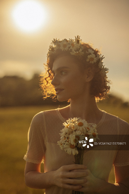 手捧鲜花、头戴花环的田野美女图片素材