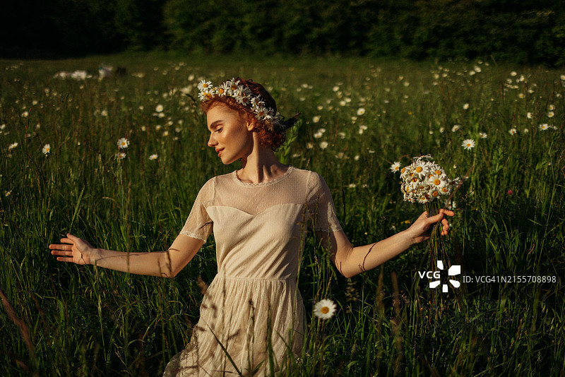 手捧鲜花、头戴花环的田野美女图片素材