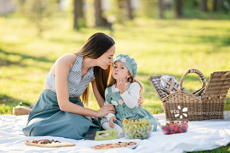 快乐的母亲和女儿在户外野餐图片素材