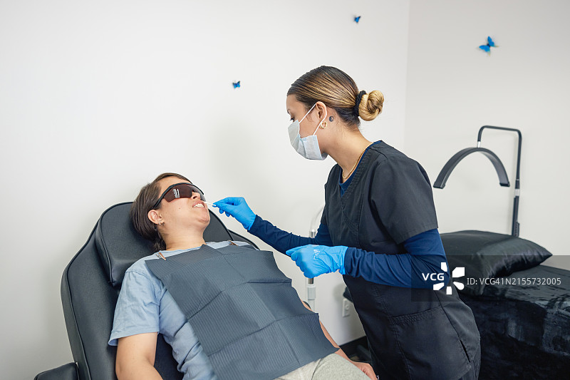 年轻的墨西哥女技师在牙齿美白沙龙与女客户在一起图片素材