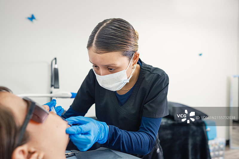 年轻的墨西哥女技师在牙齿美白沙龙与女客户在一起图片素材