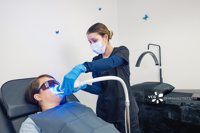 年轻的墨西哥女技师在牙齿美白沙龙与女客户在一起图片素材