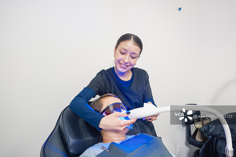年轻的墨西哥女技师在牙齿美白沙龙与女客户在一起图片素材