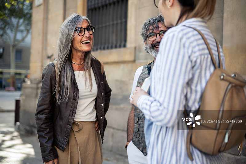 快乐的老年夫妇在度假时与一位怀孕的年轻女人交谈图片素材