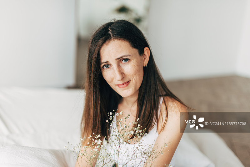 看向别处。年轻美丽的微笑女性的特写肖像，未化妆，在明亮的工作室背景下隔离。健康、福祉、健身、化妆品、牙齿健康概念。自然美图片素材