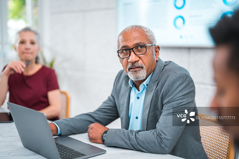 年长的混血商务主管在会议中使用笔记本电脑图片素材