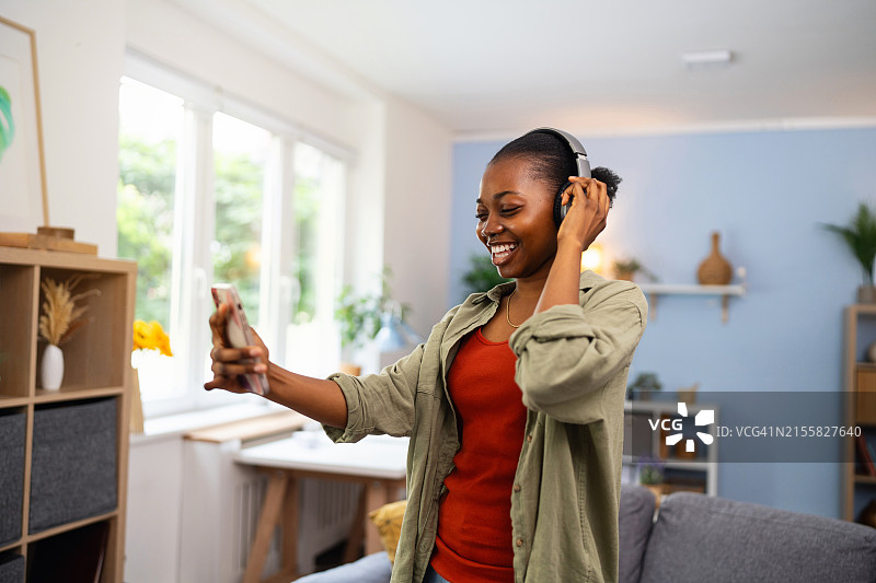 年轻黑人女子用手机听无线耳机音乐图片素材