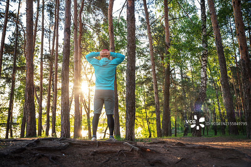 日落时分在树林跑步后休息的运动男人图片素材