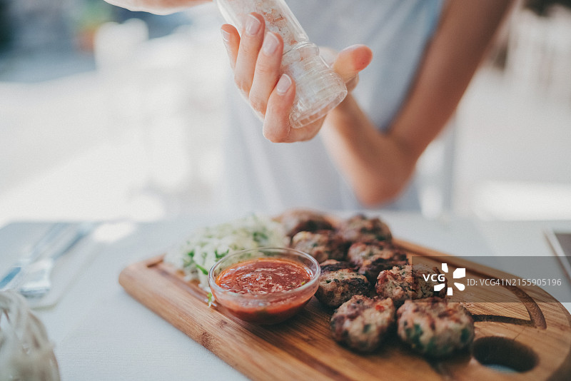 餐厅里给烤肉丸撒盐的女人图片素材