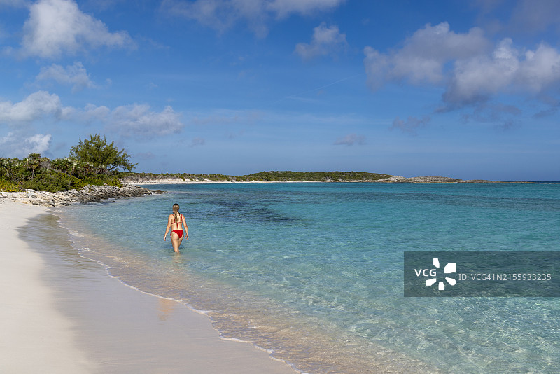 年轻女人走在埃克苏马群岛翠绿的海水中图片素材