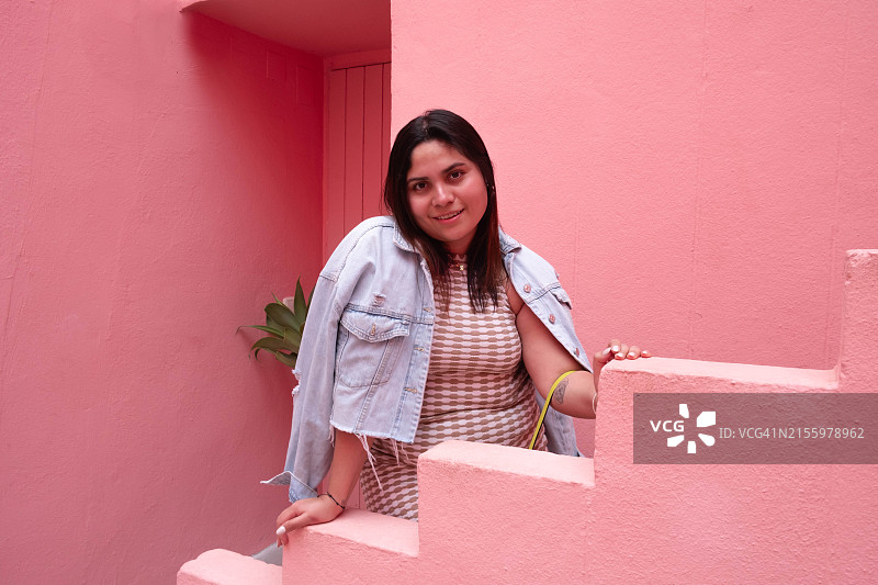 站在粉色建筑拐角处的拉丁裔女人图片素材