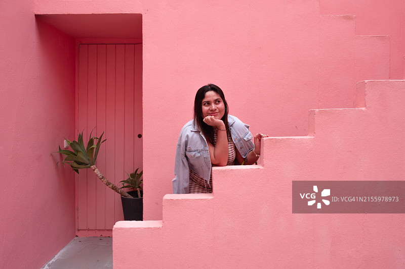 站在粉色建筑拐角处的拉丁裔女人图片素材