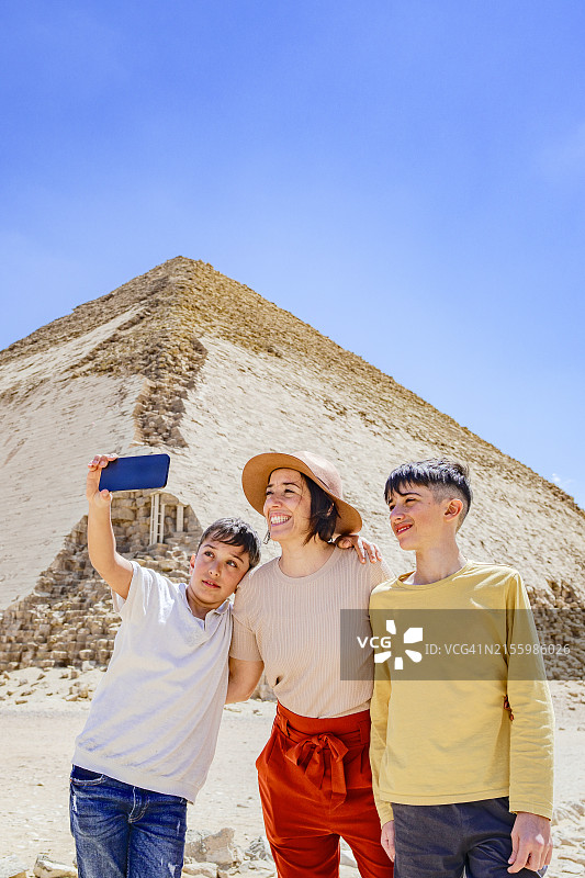 快乐的一家人在弯曲金字塔前自拍图片素材