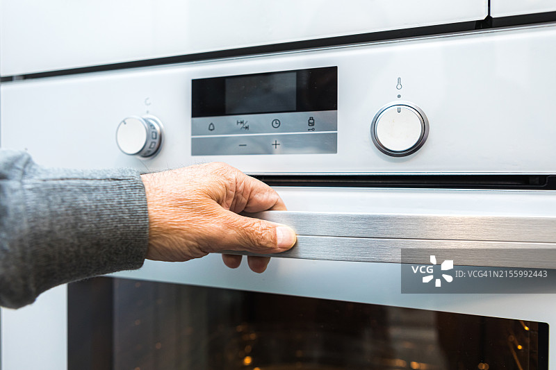 一名男子打开了电烤箱的门，内置烤箱、电器、加热、电力、烹饪概念素材图片素材
