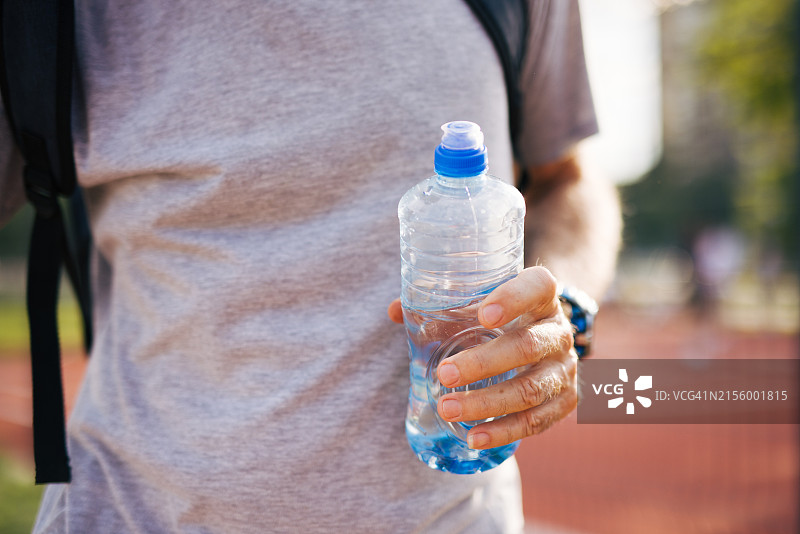 年长的男人在户外锻炼，手持水瓶特写图片素材