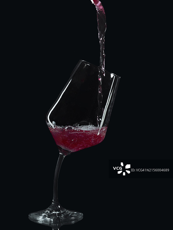 红酒倒入倾斜的葡萄酒杯中图片素材
