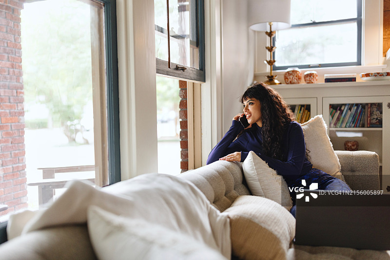 在客厅放松时用智能手机交谈的女人图片素材