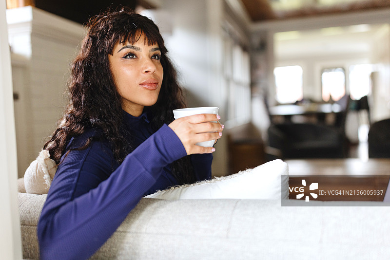 快乐的女人一边喝茶一边望向窗外图片素材