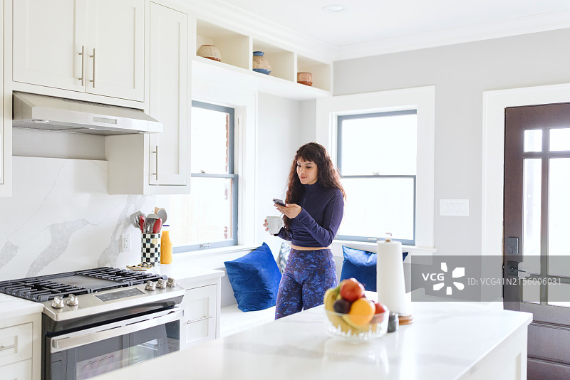 在厨房用智能手机打字的女人图片素材