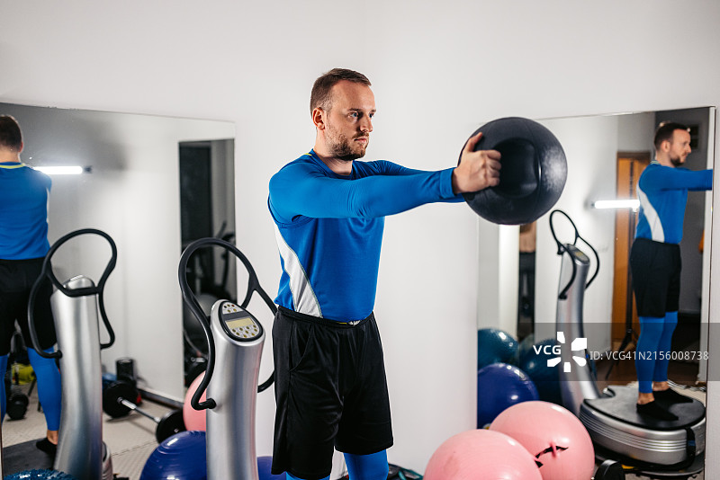 年轻男人在健身房用平衡球锻炼图片素材