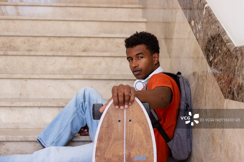 大学生在台阶上滑着滑板放松图片素材