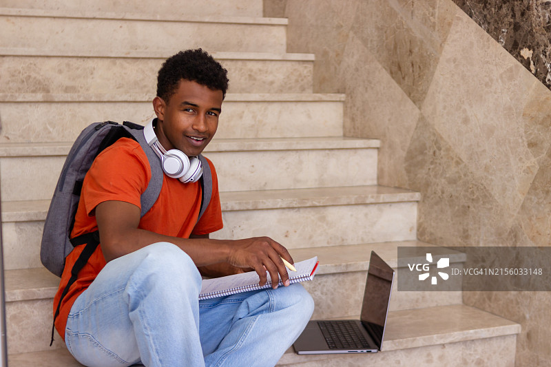 在大学台阶上用笔记本电脑学习的年轻学生图片素材