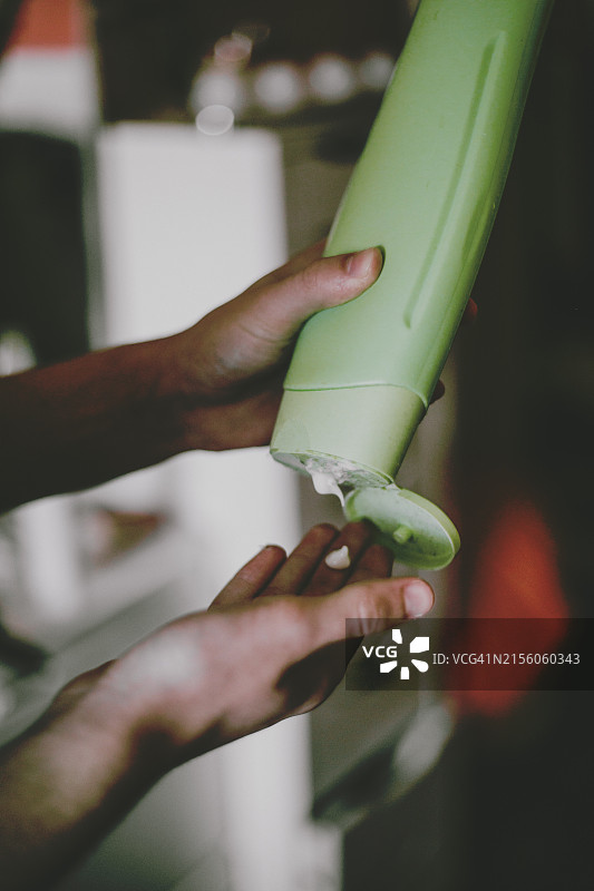 男子手持面霜软管并将内容物挤到另一只手上图片素材