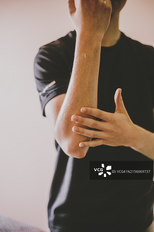 男人将润肤露擦到手臂和手指上图片素材