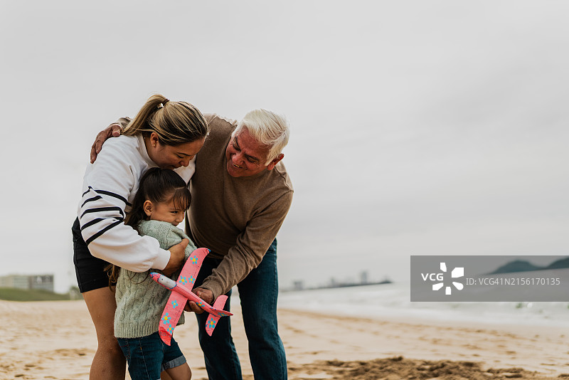 在海滩上玩玩具飞机的家庭图片素材