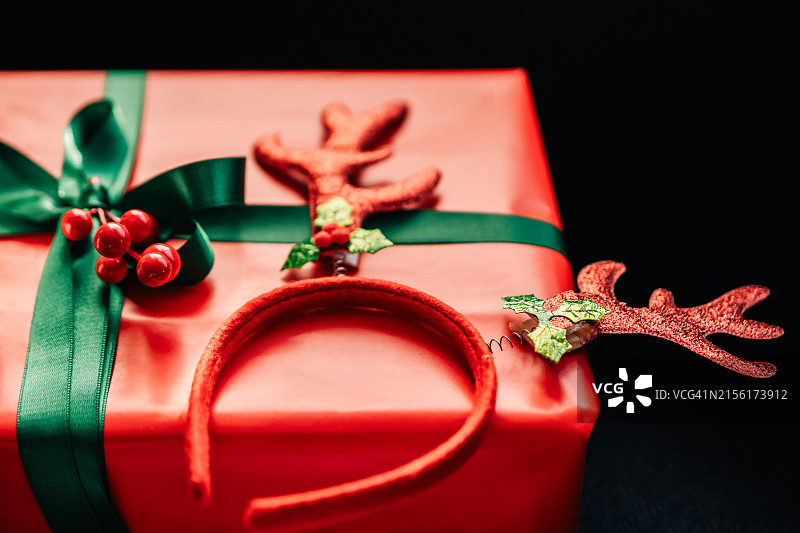 带绿色丝带的红色圣诞礼物特写，礼物上有驯鹿配饰图片素材