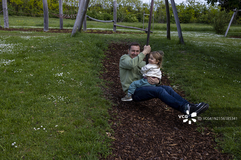 年长的父亲和小儿子在游乐场玩滑索图片素材