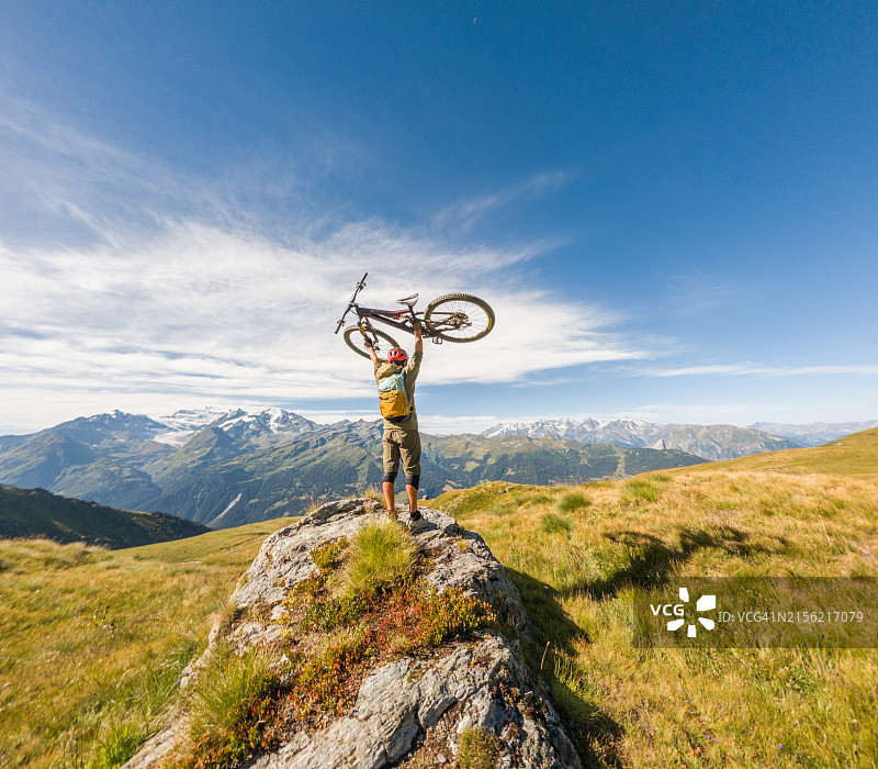 山地自行车手在阿尔卑斯山风景中举起自行车图片素材