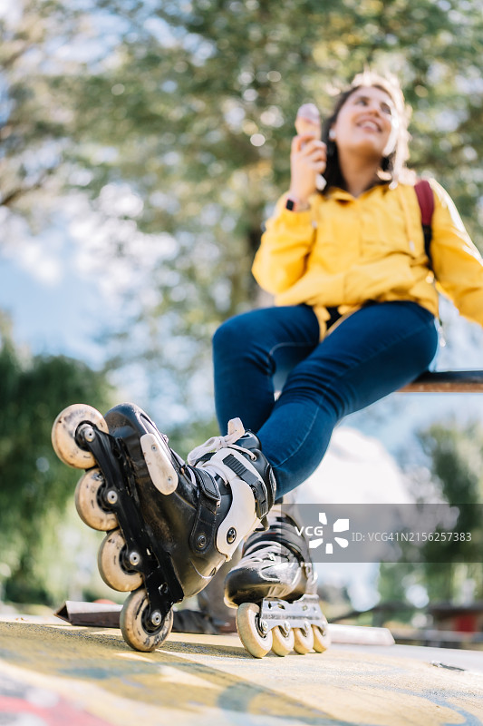 女人坐在长椅上，带着滑板吃冰淇淋图片素材