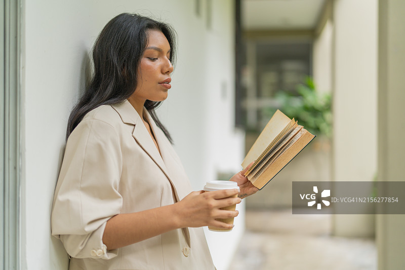 女人靠墙读书喝咖啡图片素材