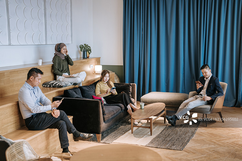 在轻松的共享创意空间休息和工作的亚洲同事们图片素材