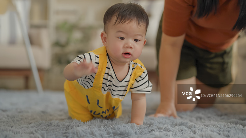 快乐的亚洲宝宝在家里练习爬行，玩耍图片素材