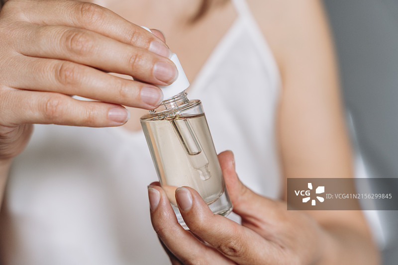 女人手拿滴管玻璃瓶，内含保湿抗衰老精华或面部护肤油图片素材